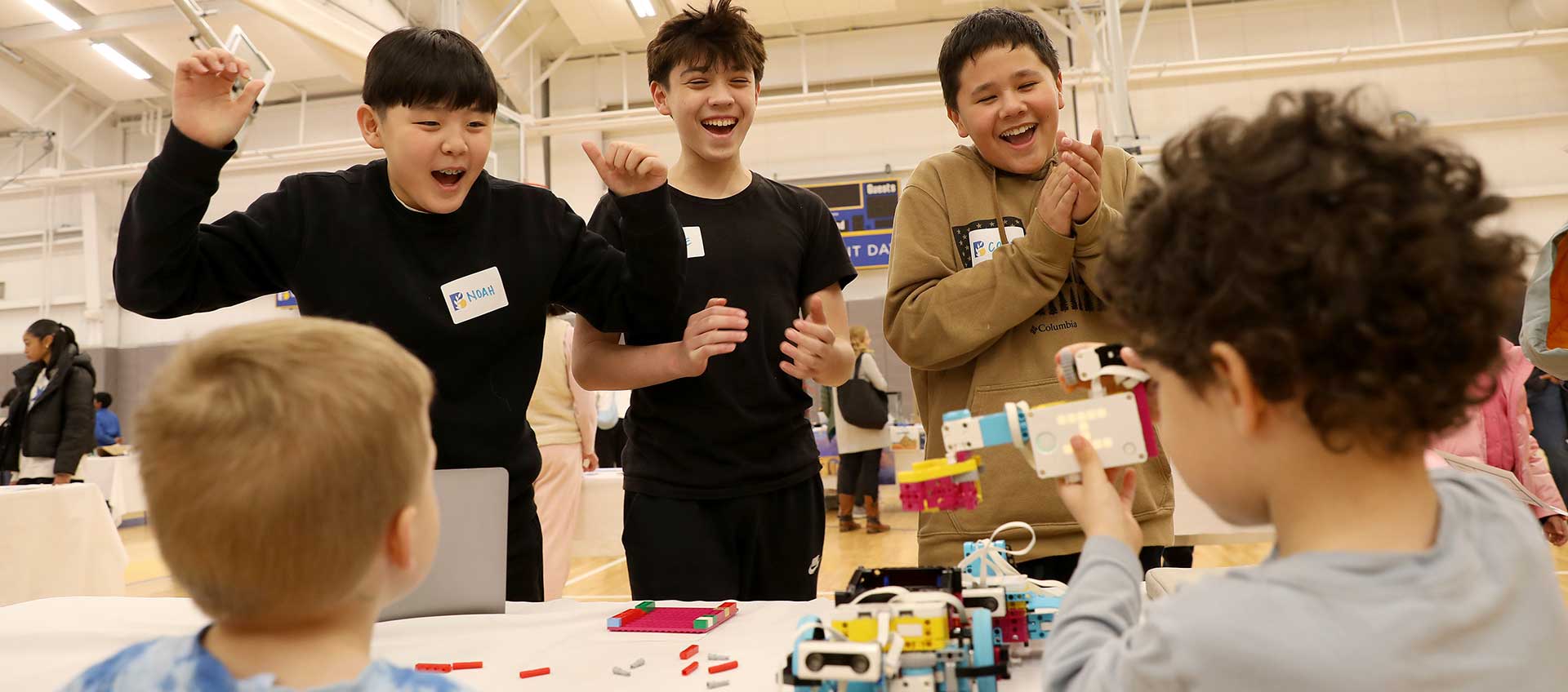 Three middle school boys cheer on two kindergartners at the STEAM Expo